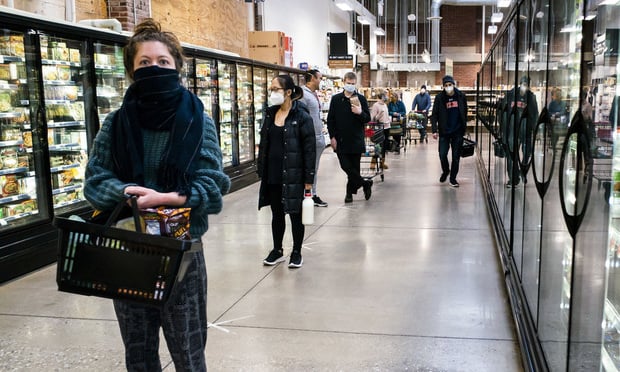 Customers wait in line at a MOM supermarket in Baltimore adhering to social distancing rules, aided by markings on the floor spread 6 feet apart, in response to the coronavirus, on April 18