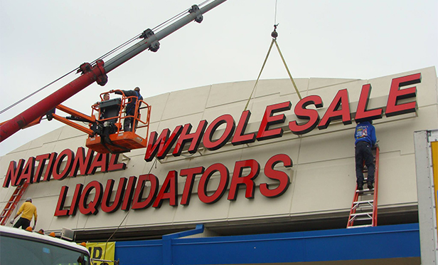 Workers install signage at new National Wholesale Liquidators location, 9000 Orthodox St., Philadelphia, PA. The new location opens May 17.